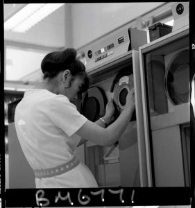 B&W image of a women loading a magnetic tape reel into a computer